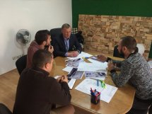 Четверо чоловіків спілкуються між собою сидячі за столом.