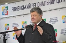 Чоловік щось розповідає у мікрофон на фоні банера.