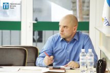 Чоловік у блакитній сорочці сидить за столом.