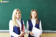 Дві жінки стоять біля шкільної дошки.