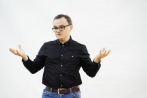 Чоловік в окулярах щось розповідає піднявши руки.