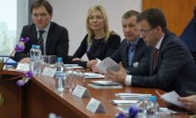 Троє чоловіків та жінка у чорному одязі сидять за столом у приміщенні.