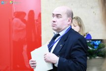 Чоловік у діловому костюмі тримає папери у руках.