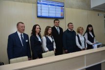 Чотири жінки та троє чоловіків стоять за реєстраційною стійкою.