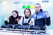 Чоловік з жінкою та ді-джей позують біля діджейського обладнання.