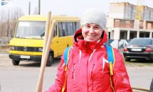 Жінка у червоній куртці посміхається.