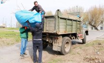 Чоловіки завантажують сміття на вантажівку.