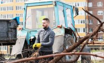 Чоловік стоїть біля трактора.