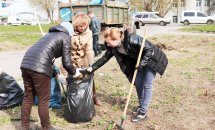 Троє жінок збирають сміття у чорний пакет.