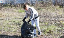 Чоловік збирає сміття у чорний пакет.