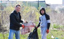 Двоє чоловіків збирають сміття у чорний пакет.