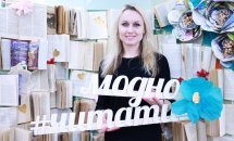 Жінка зі світлим волоссям фотографується біля фотозони з книг.