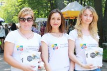 Три жінки у білому одязі тримають у руках роздаткові матеріали.