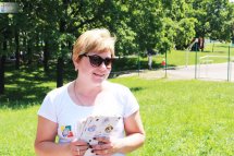 Жінка в сонцезахисних окулярах тримає у руках роздаткові матеріали.
