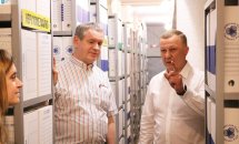 Двоє чоловіків перебувають у приміщенні зі стелажами на яких розміщенні документи.