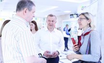 Двоє чоловіків та жінка спілкуються між собою. Вони перебувають у приміщенні.