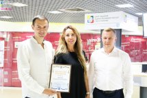 Два чоловіка та жінка фотографуються у приміщенні з грамотою у руках.