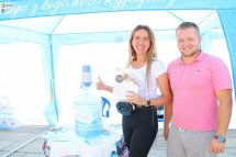 Чоловік та жінка стоять біля бутля з водою та посміхаються.