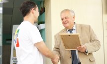 Двоє чоловіків тиснуть руки один одному та посміхаються.