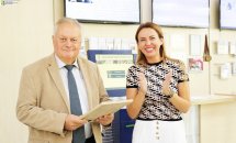 Чоловік тримає щось у руках, біля нього стоїть усміхнена жінка.