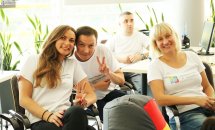 Чоловік та дві жінки сидять усміхнені у приміщенні та позують для фото. 
