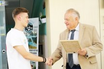 Чоловік старшого віку тисне руку хлопцеві.