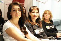 Троє жінок сидять у приміщенні та дивляться у камеру.