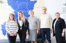 Чоловік та чотири жінки позують на фоні синьої карти Рівненської області.