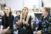 Жінка з світлим волоссям щось розповідає, а ще дві жінки сидять біля неї з обох сторін.