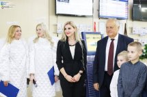 Жінка, чоловік, двоє дітей та дві жінки в костюмах ангелів стоять у приміщенні.