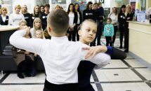Хлопчик та дівчинка танцюють у парі, позаду стоять люди.