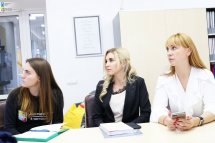 Три жінки сидять за столом та дивляться убік.