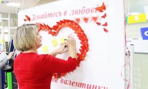 Жінка у червоній сукні пише щось на плакаті.