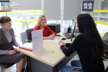 Три жінки сидять за робочим столом та спілкуються між собою.