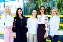 П'ять жінок у вишиванках позують біля приміщення.
