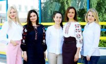 П'ять жінок у вишиванках позують біля приміщення.