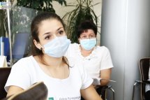 Дві жінки у захисних масках сидять у приміщенні.