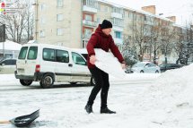 Чоловік у верхньому одязі несе брилу снігу.