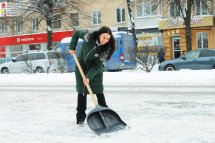Жінка прибирає сніг лопатою надворі.