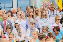 Діти та дорослі у вишиванках усміхаються і махають руками.