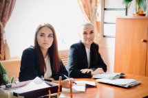 Жінки в чорних піджаках сидить за столом у кабінеті.