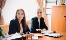 Жінки в чорних піджаках сидить за столом у кабінеті.