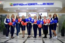 Жінки в офіційному одязі тримають кульки з логотипом.