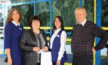 Працівниці у синіх сукнях позують з відвідувачами для фото.