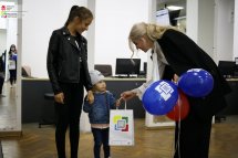 Відвідувачка заходу отримує подарунковий пакет.
