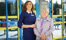 Співробітниця в синьому костюмі фотографується з жінкою похилого віку.