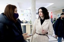 Жінка у костюмі спілкується з іншою жінкою.