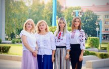 Чотири жінки у вишитих сорочках стоять на тлі зеленої зони.