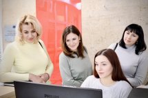 Жінки розглядають щось на комп’ютері, ведучи діалог.
