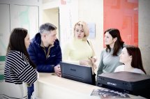 Група людей обговорюють щось дивлячись на комп'ютер.